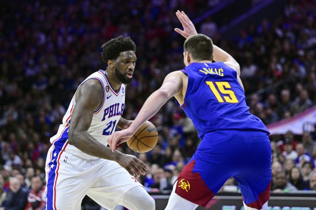 Philadelphia 76ers' Joel Embiid, left, dribbles the ball against Denver Nuggets' Nikola Jokic during the second half of an NBA basketball game, Saturday, Jan. 28, 2023, in Philadelphia. (AP Photo/Derik Hamilton)